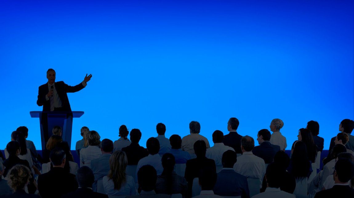 Speaker at a podium addressing an audience at a non-profit association event by Blast Marketing Agency in NYC.